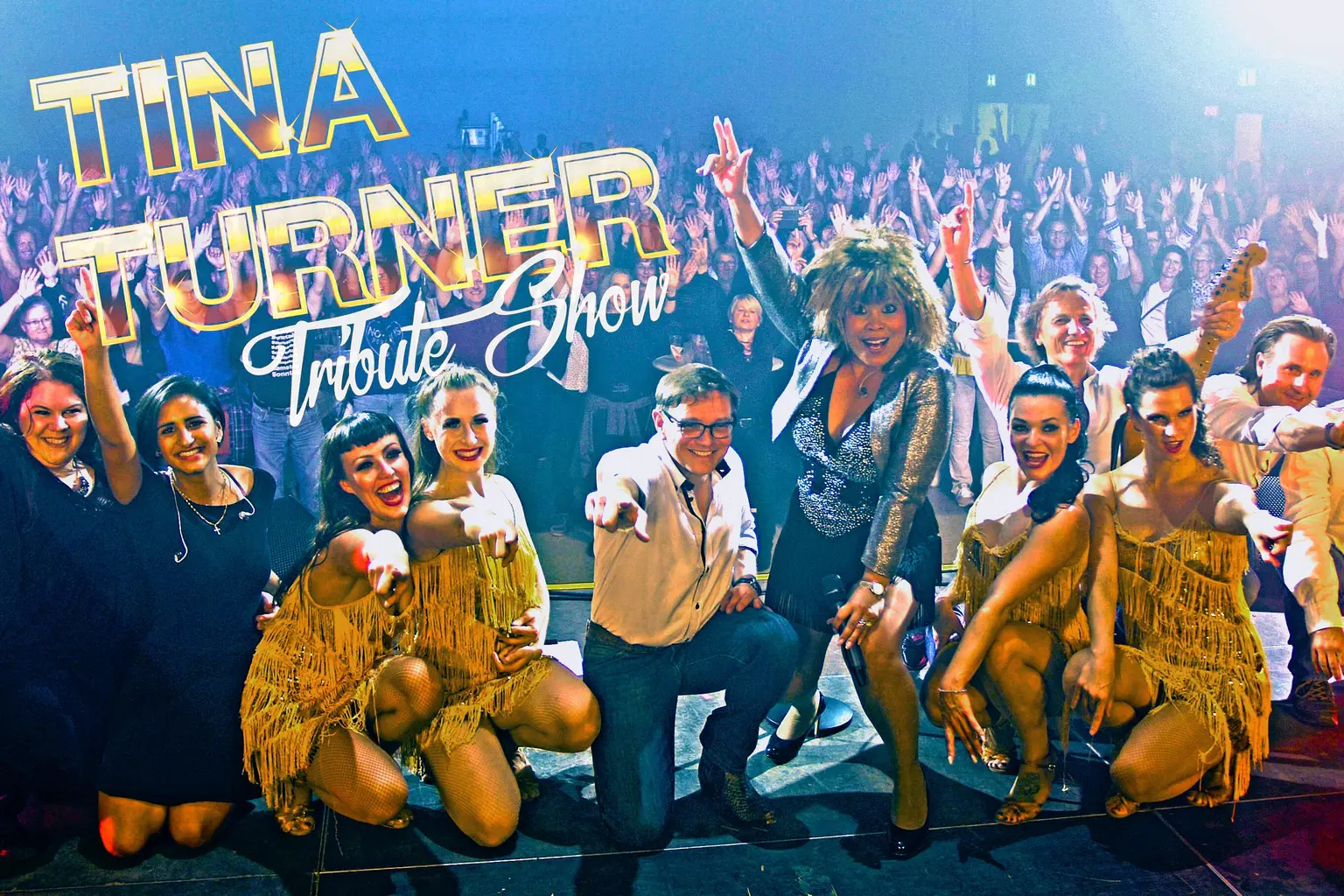 Tina Turner Tribute Show mit Band, Tänzerinnen und Publikum vor grossem Show-Logo